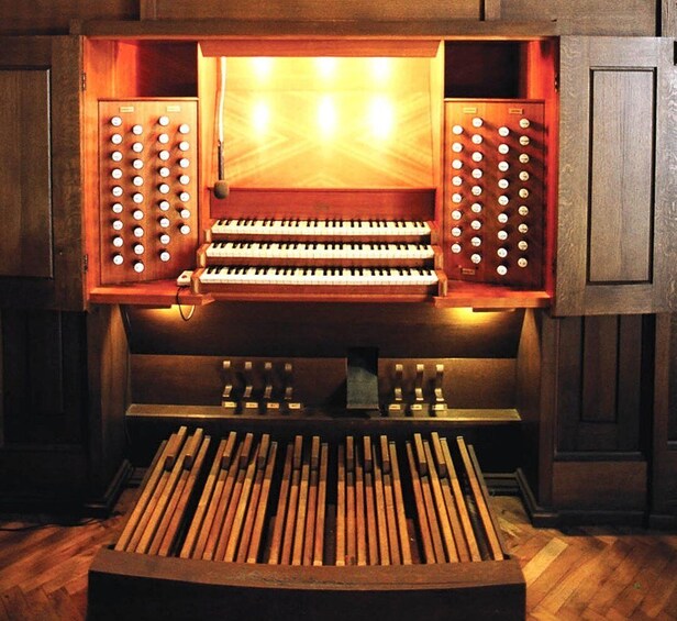 A wooden organ with illuminated keys and a bench in front. 4