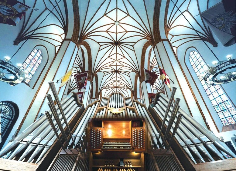 A cathedral interior with a high vaulted ceiling, stained glass windows, and a pipe organ. 1