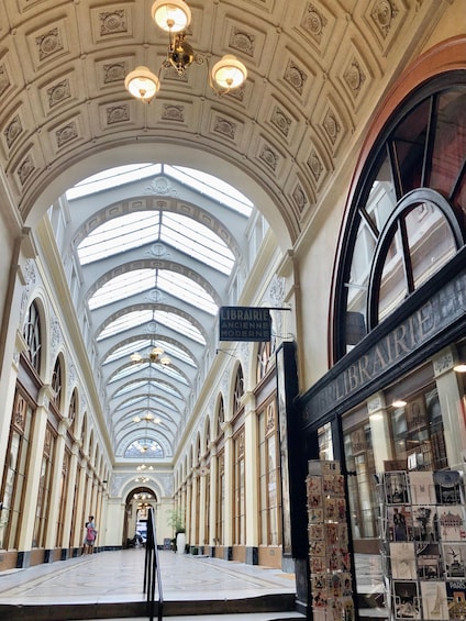 A grand library with a high arched ceiling and skylights, featuring ornate columns and a central staircase. 2