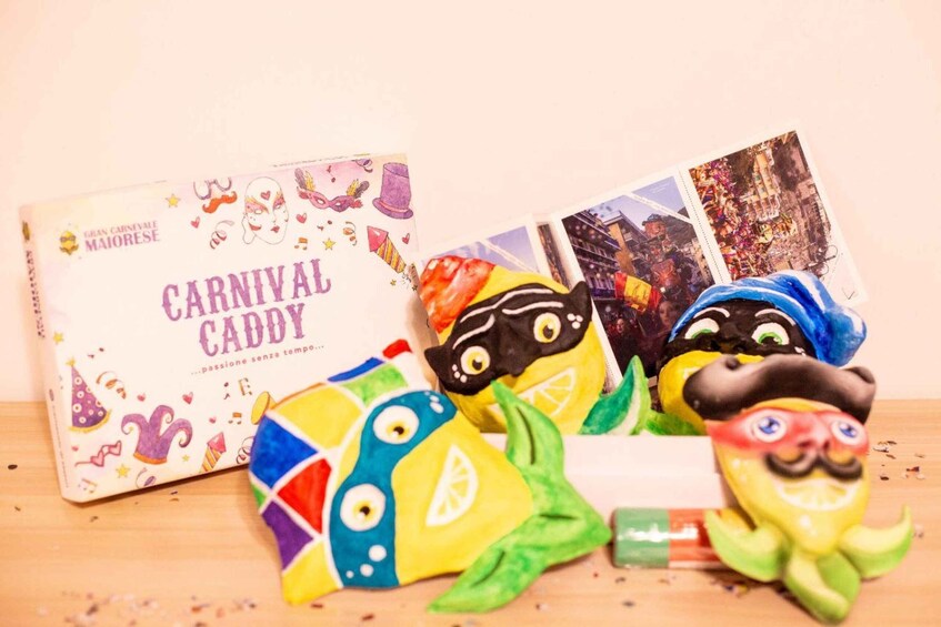 A book titled 'Carnival Caddy' and colorful papier-mâché birds on a wooden surface. 2
