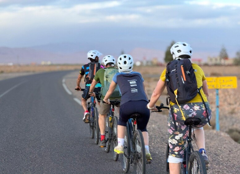 A group of cyclists on a paved road with a mountainous landscape in the background. 5