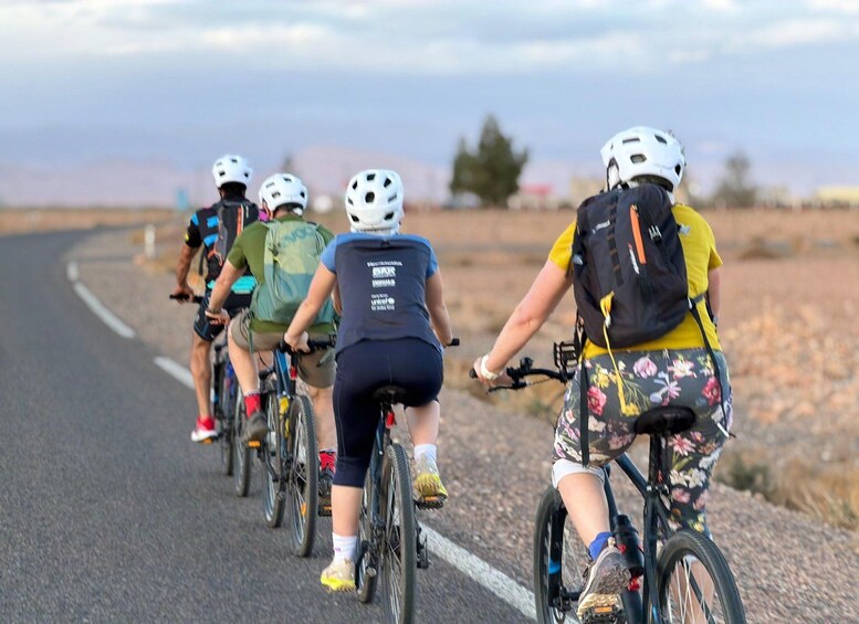A group of cyclists on a paved road with a clear sky. 4