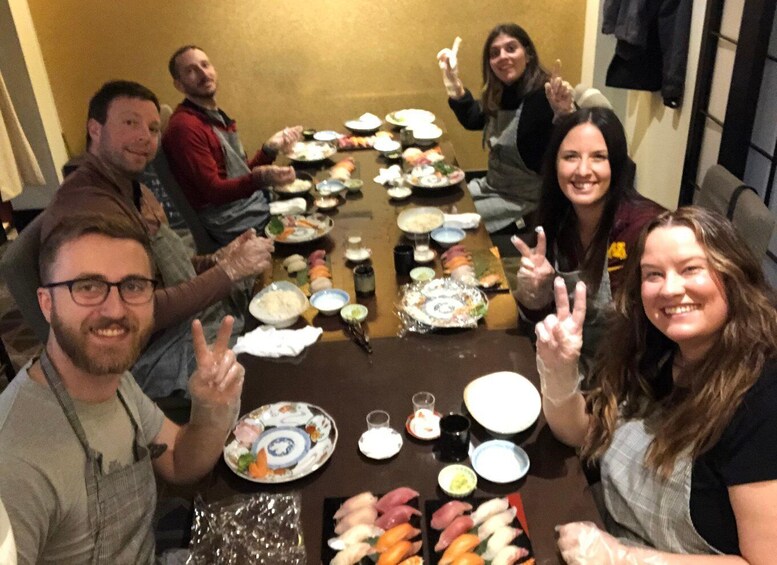 Eine Gruppe von Menschen sitzt an einem Tisch mit verschiedenen Speisen, darunter Sushi. 2