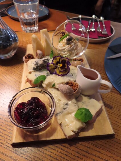 A wooden board with various food items including cheese, a bowl of berries, and a glass of water. 5