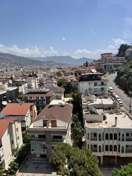 A cityscape with a mix of modern and traditional architecture, a winding road, and distant mountains. 2
