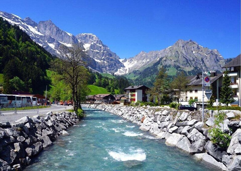 A river flowing through a mountainous area with rocky banks and houses along the side. 5