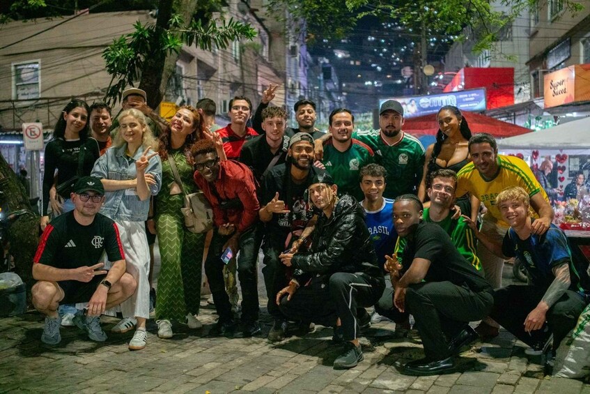 A group of people posing for a photo on a city street at night. 1