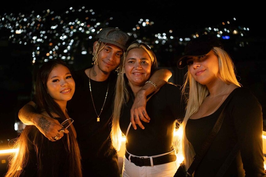 Four people standing together with a cityscape in the background. 2