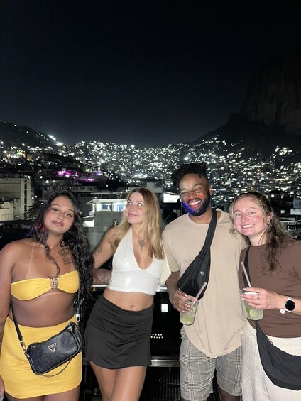 A group of people posing on a rooftop with a cityscape and mountains in the background. 5