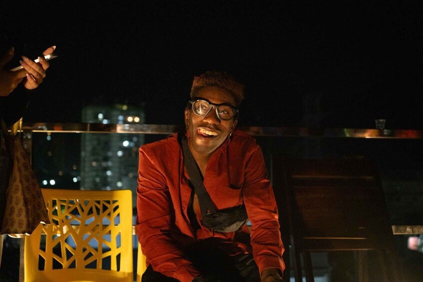 A person in a red jacket sitting on a yellow chair with a cityscape in the background. 4