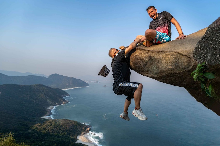 A person climbing a rock with a scenic ocean view in the background. 2
