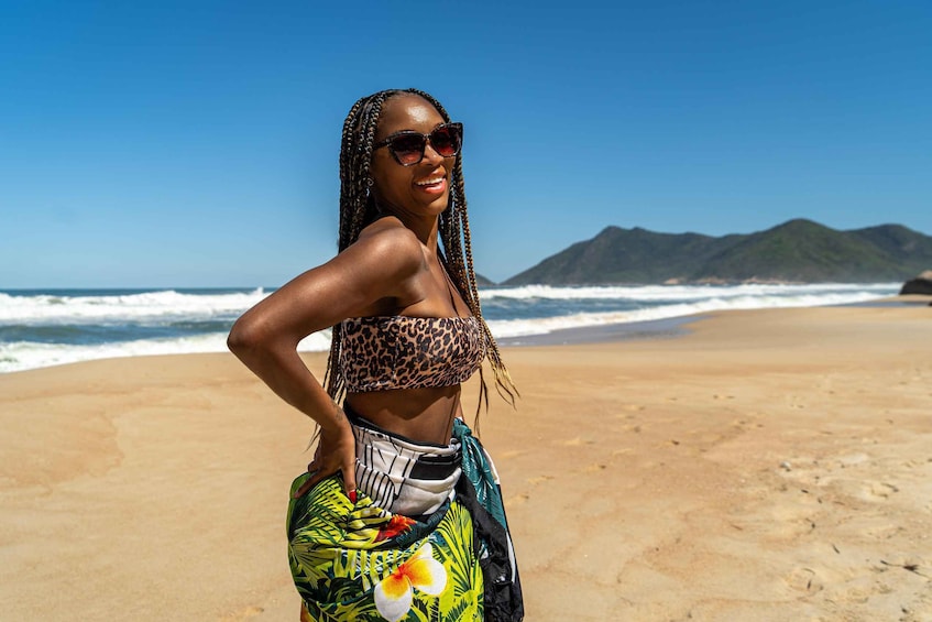 A person on a beach with ocean waves and mountains in the background. 3