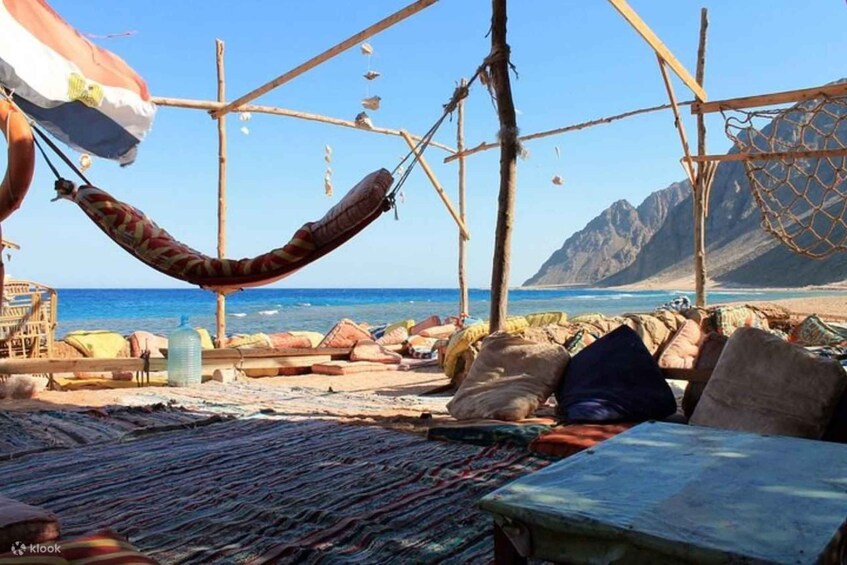 Een strand met een hangmat, houten constructies en een bergachtige achtergrond. 3