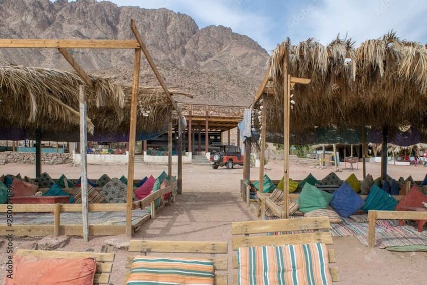 A desert campsite with wooden structures and colorful cushions. 5