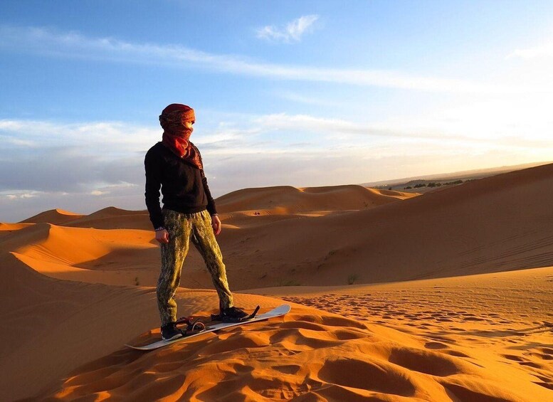 A person standing on a snowboard in a desert with sand dunes. 2