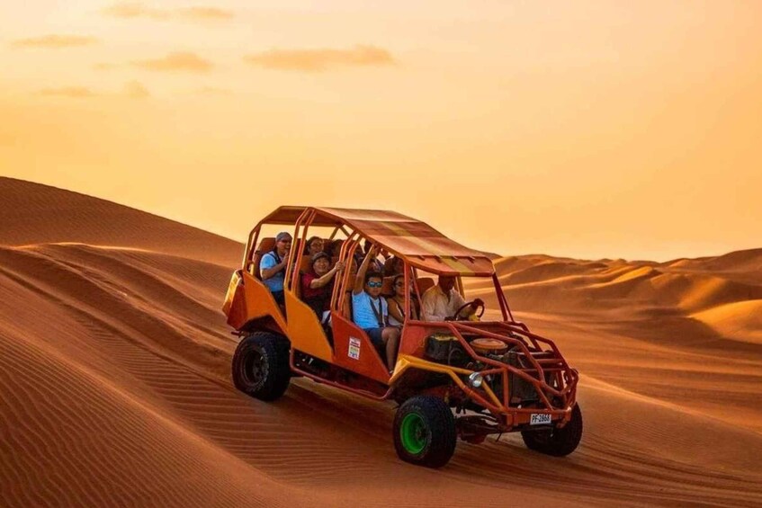 A dune buggy with passengers driving through a desert landscape. 4