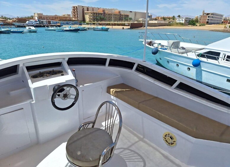 A boat's deck with a steering wheel, a cushioned seat, and a small table. 4