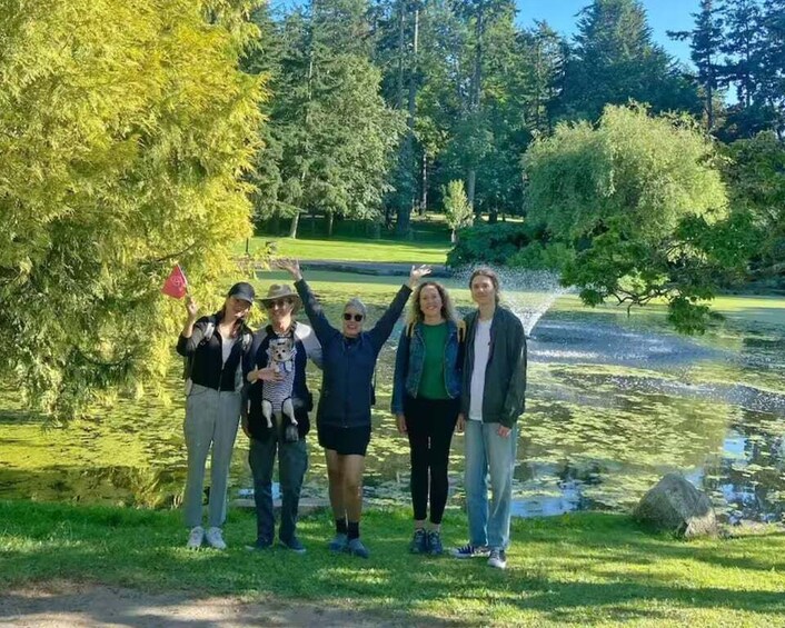 A group of people standing in a park with a pond and trees in the background. 4
