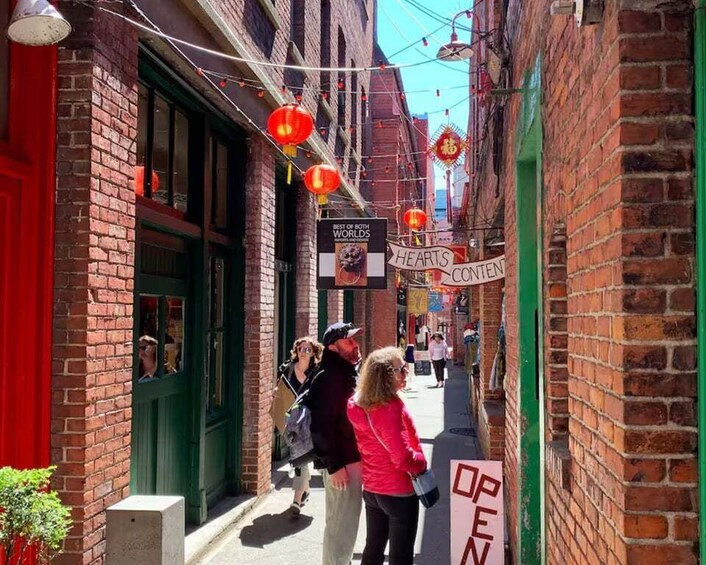 A narrow alley with brick buildings, red lanterns, and signs indicating a restaurant. 3