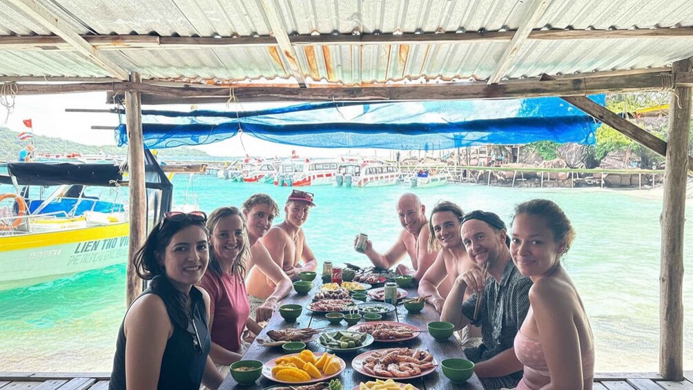 A group of people dining on a boat with a view of a harbor and boats in the background. 4
