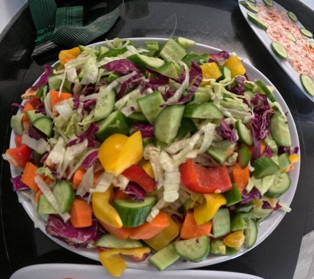 A plate of mixed vegetable salad with cucumbers, bell peppers, and shredded cabbage. 1