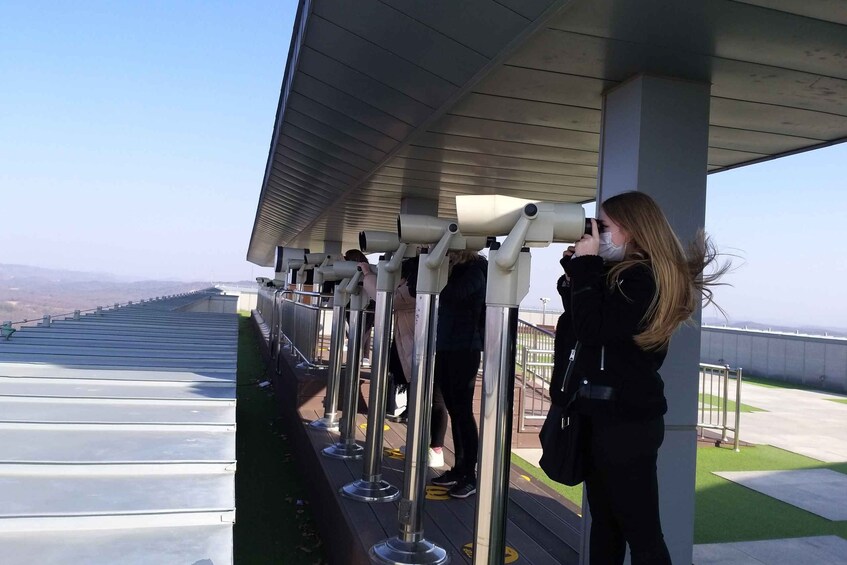 A person using a telescope at an observation deck. 2