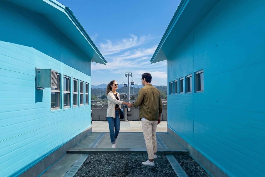 Two people shaking hands on a rooftop with a clear sky and mountains in the background. 3