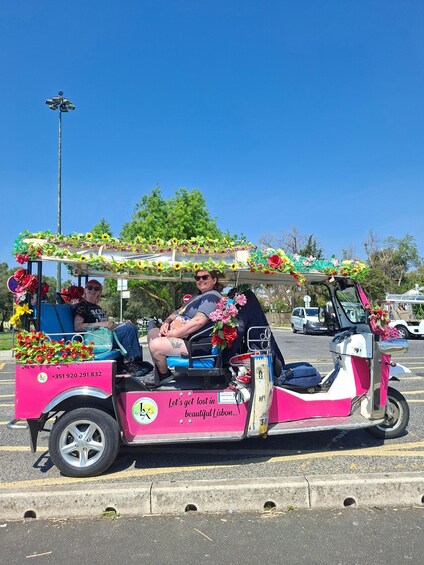 A pink and white motorcycle decorated with flowers and a sign that says 'Let's get lost in beautiful Lisbon.' 3