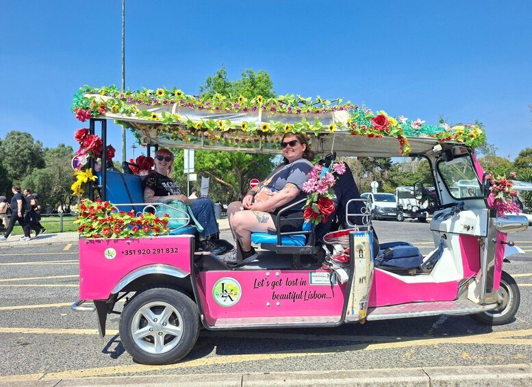 A pink and white trolley decorated with flowers and greenery, parked in a parking lot. 4