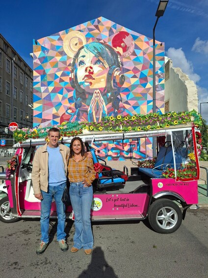 A colorful bus with a mural and flowers, parked on a street. 1