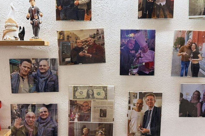 A wall with various photographs and a dollar bill. 5