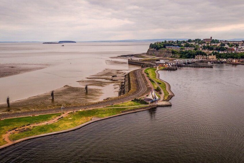 A coastal landscape with a river curving through a town, a bridge, and distant landforms. 3
