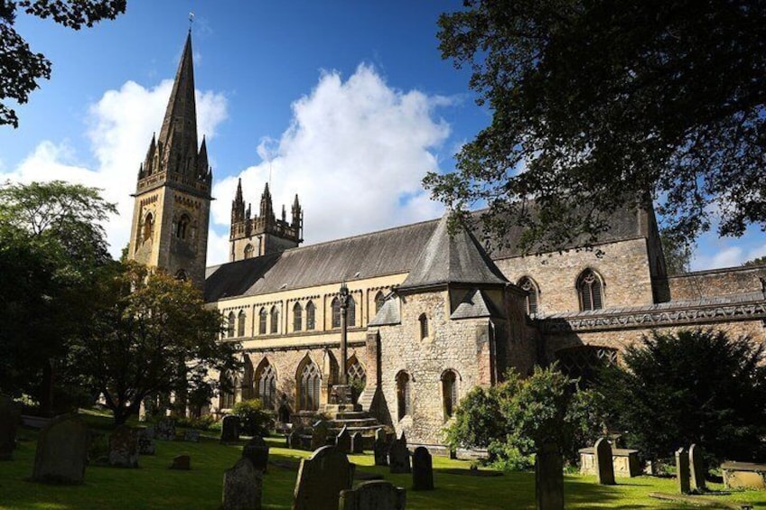 A historic church with a prominent tower and a cemetery in the foreground. 1