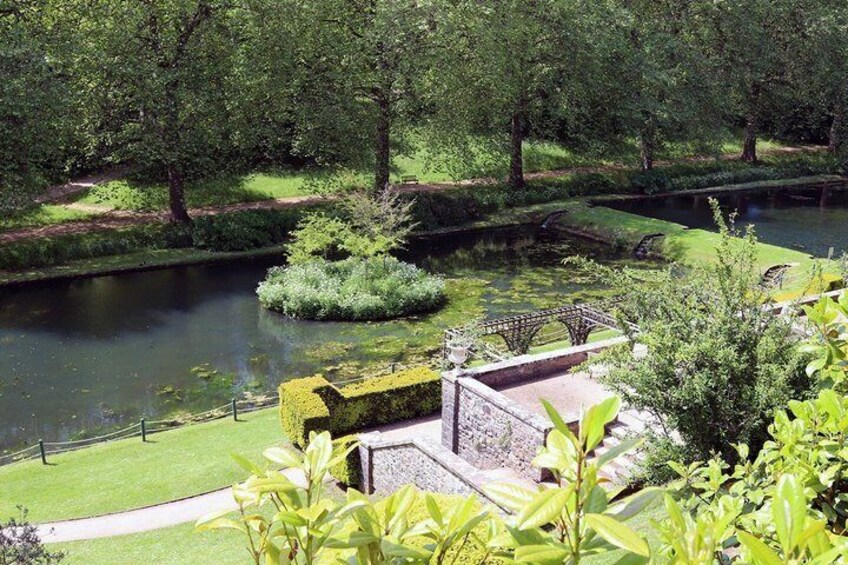A serene garden with a pond, a bridge, and well-manicured trees. 4