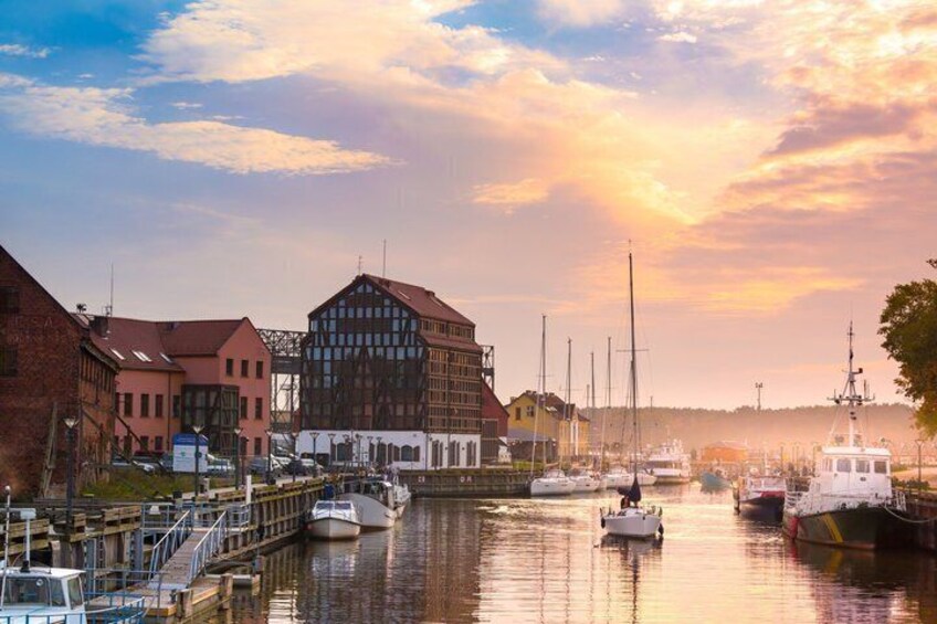 A harbor with boats, a wooden building, and a sunset. 1