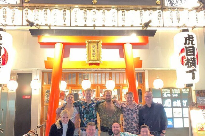 A group of people in front of a traditional Japanese building with a torii gate. 4