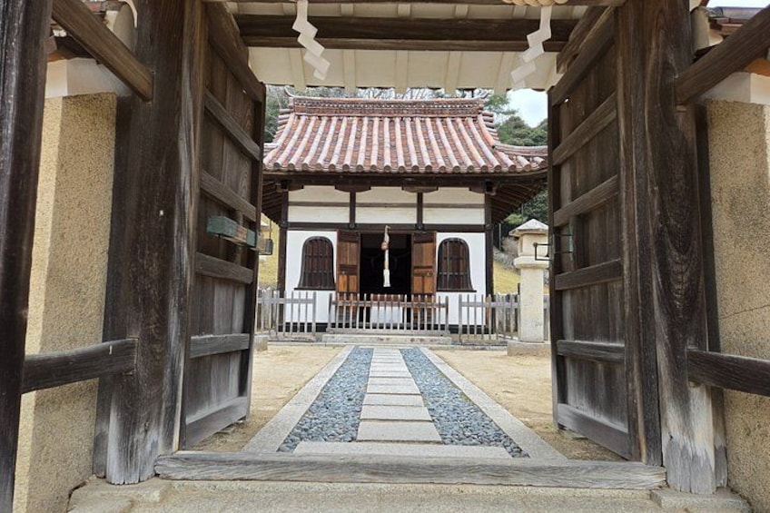 A traditional Japanese gate leading to a building with a tiled roof. 2