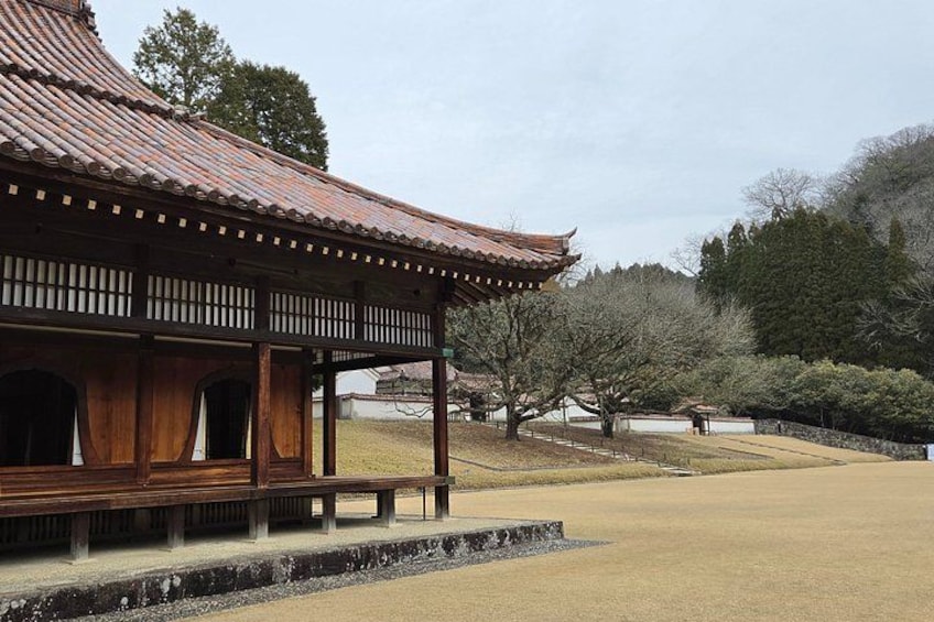 A traditional wooden pavilion with a tiled roof, surrounded by a manicured lawn and trees. 5