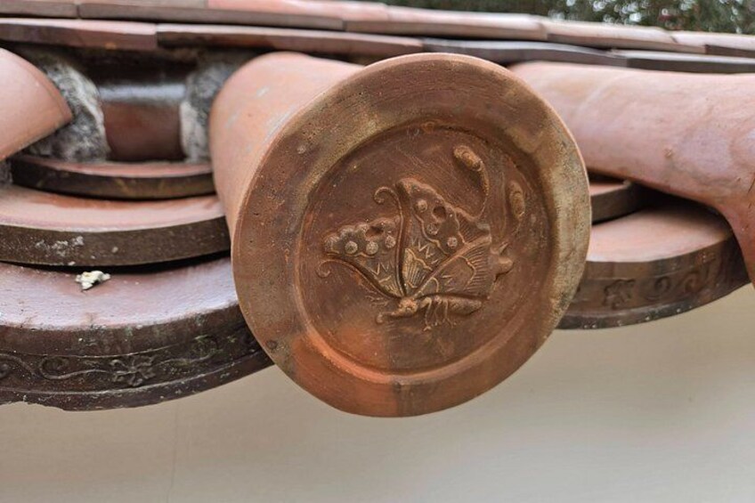 A close-up of a copper-colored metal object with embossed designs, possibly a part of a larger structure. 3
