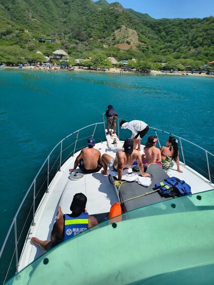 A boat with people on board, a beach, and a mountainous landscape in the background. 2