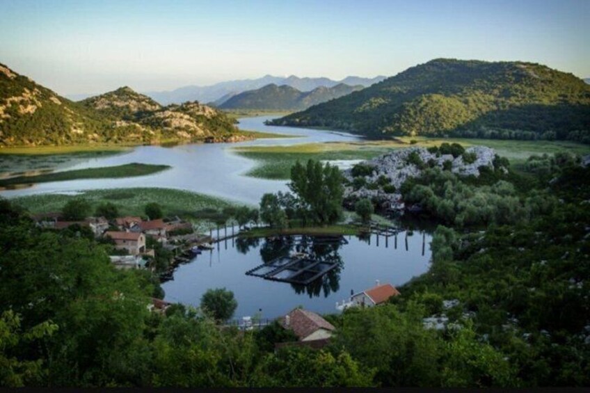 Un lago circondato da colline, un molo e delle case. 5