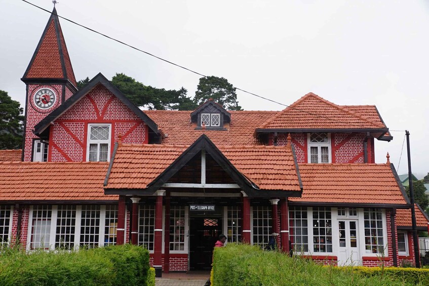 A red brick building with a clock tower, a post office sign, and a triangular roof. 2