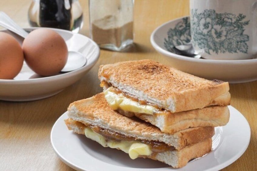 A sandwich on a plate with eggs and a cup in the background. 2