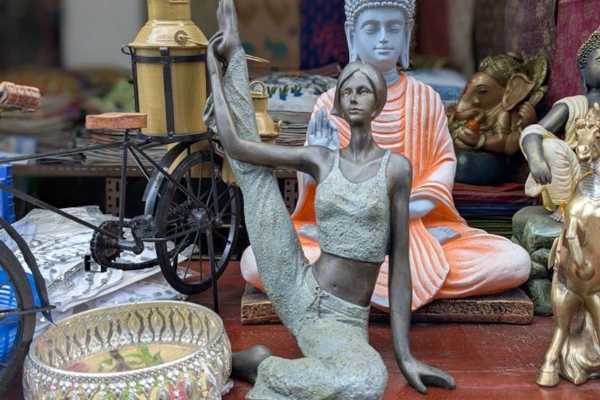 Eine Statue einer Frau in dynamischer Pose, ein sitzender Buddha sowie verschiedene weitere Statuen und Dekorationsobjekte. 4