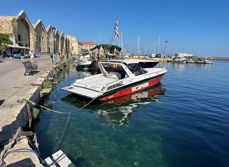 A marina with boats docked, a clear blue sky, and historic stone buildings along the waterfront. 2