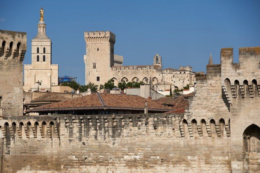 A historic stone wall with arches, a tower, and a building with a tiled roof. 5