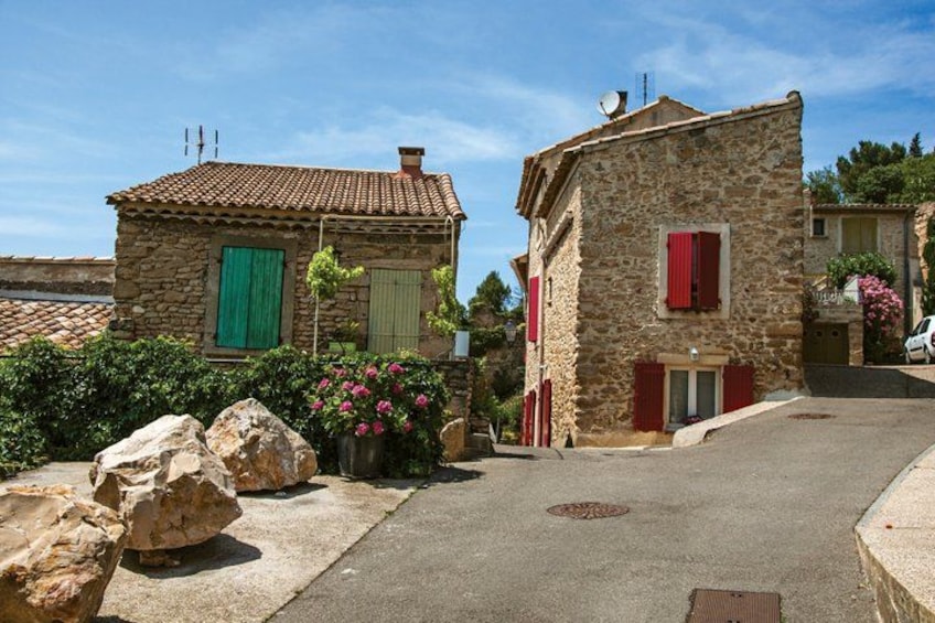A stone building with red shutters, a clear sky, and a paved street. 3
