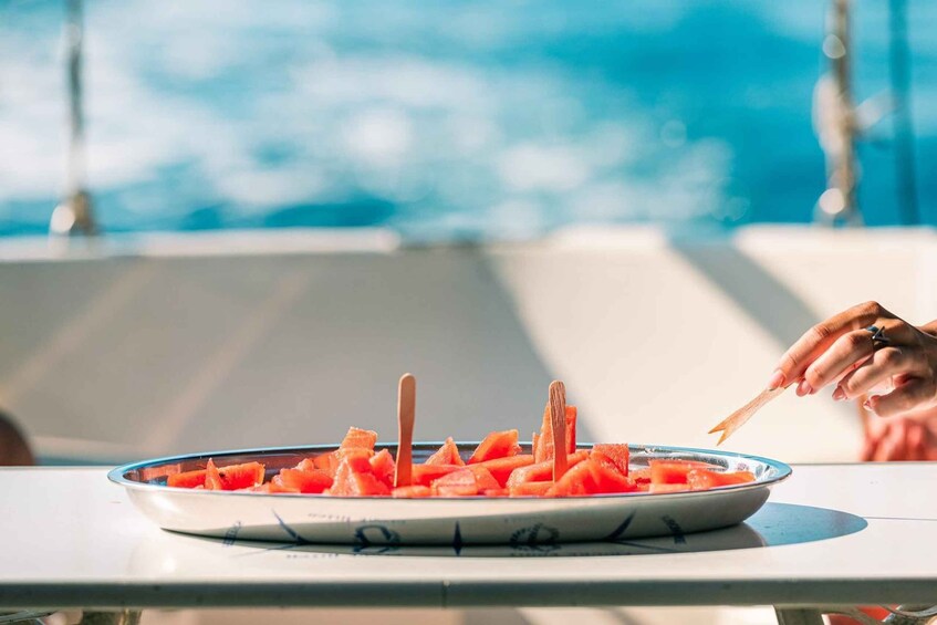 A plate of watermelon chunks on a table with a view of the ocean. 4