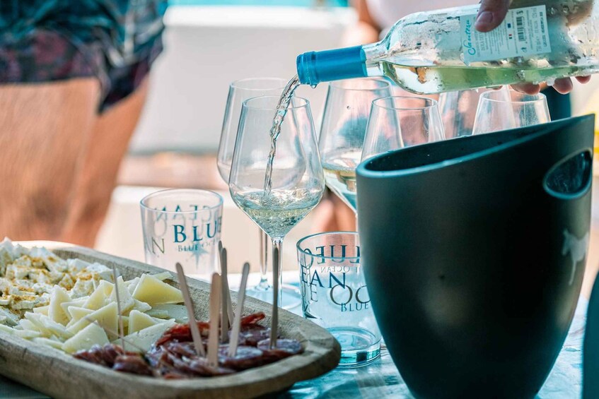 A bottle of water being poured into glasses, a plate with food, and a bucket. 2