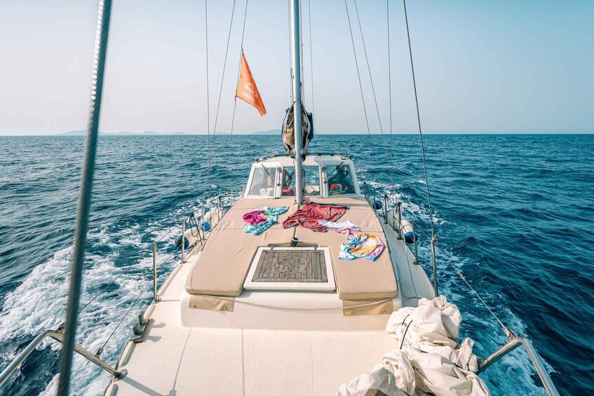 A sailboat with a flag, a steering wheel, and a deck with various items. 5
